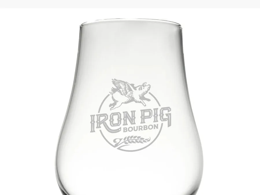 Empty glass etched with the Iron Pig Bourbon logo